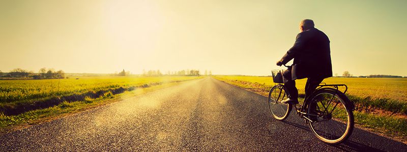 Cyklist i solljuset längs en lantväg.